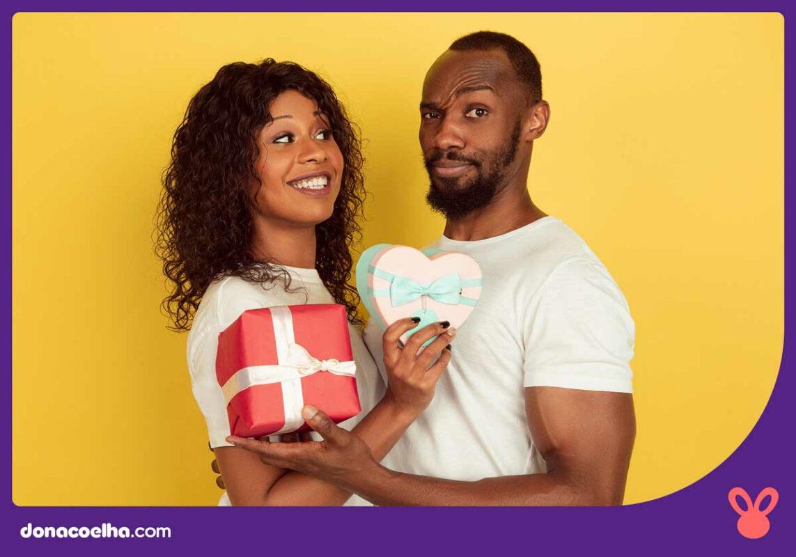 Imagem de casal se presenteando, sendo uma feliz, e o outro com olhar duvidoso