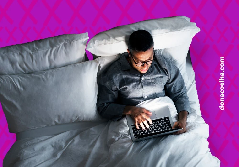 Homem de noite deitado na cama digitando no notebook