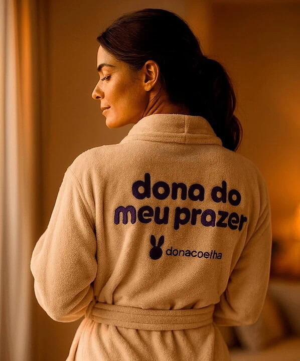 Mulher com roupão Dona Coelha, símbolo de conforto e prazer, em ambiente acolhedor.
