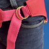 Cinto rosa com detalhes dourados, usado com jeans escuros.