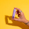 Vibrador feminino lilás para prazer e bem-estar, destaque na imagem com fundo amarelo vibrante.