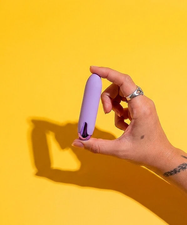 Vibrador feminino lilás para prazer e bem-estar, destaque na imagem com fundo amarelo vibrante.