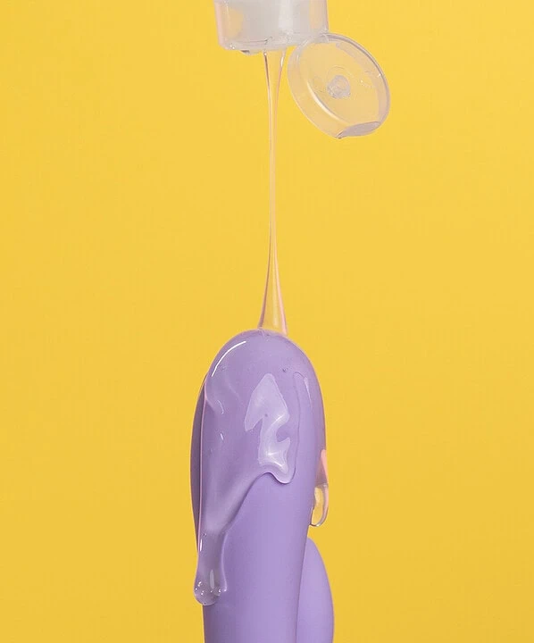 Gel lubrificante escorregando caindo em um vibrador lilás.